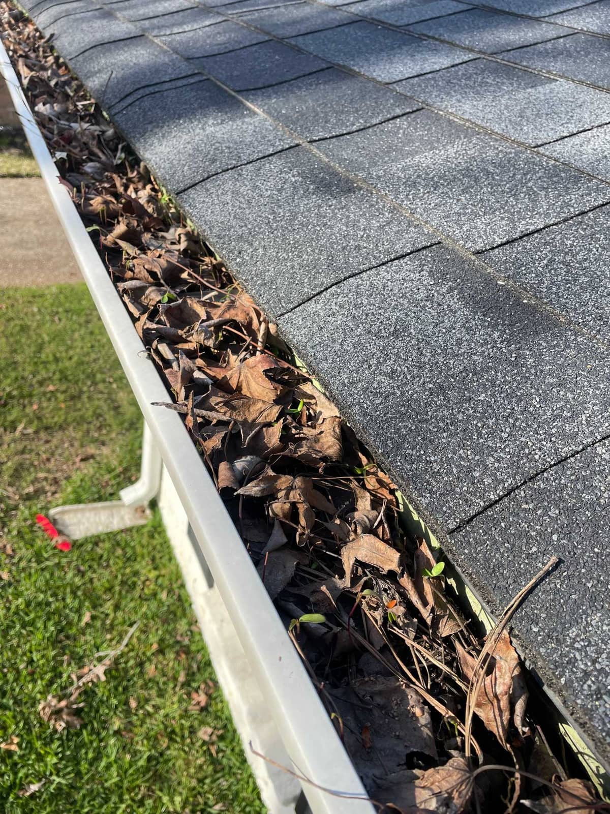 J Calvin service pro clearing gutters on a two-story home near Shenandoah, TX